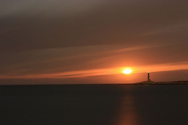 A Cape Ann lighthouse at dusk under a heavy sky