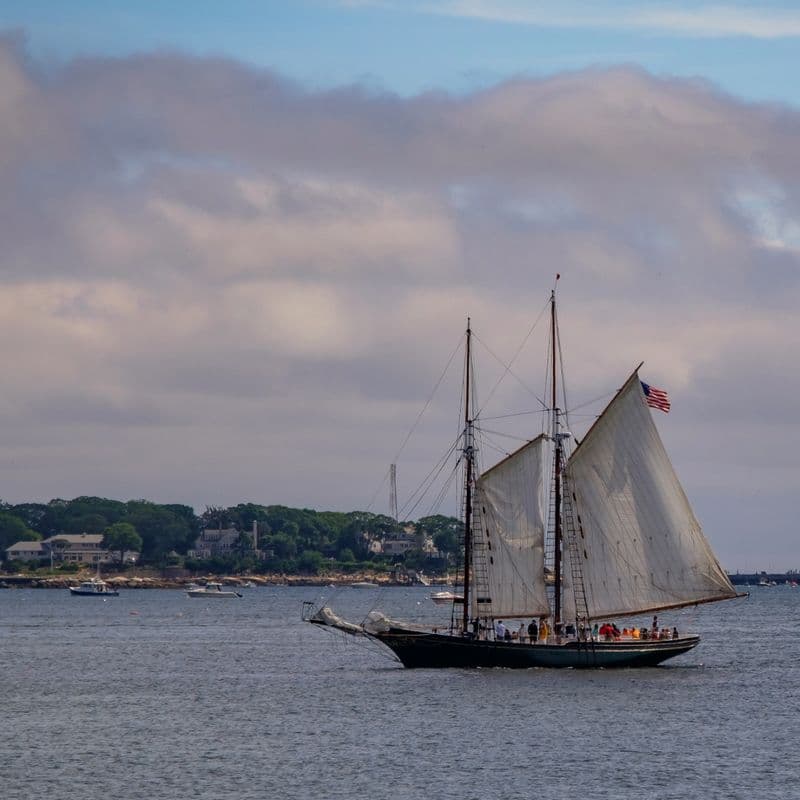 A schooner under sail on a quiet stretch of Gloucester Harbor